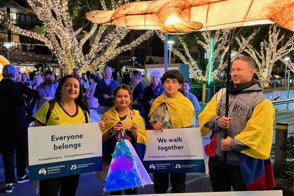 A family holding lanterns and signs at Luminous Festival at night.