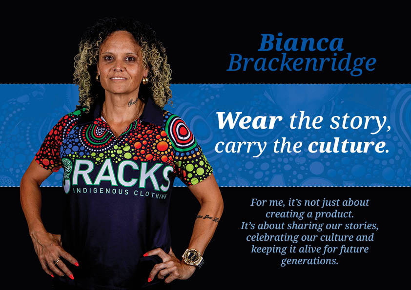 A First Nations woman with curly shoulder length hair wearing a colourful Indigenous clothing design shirt.