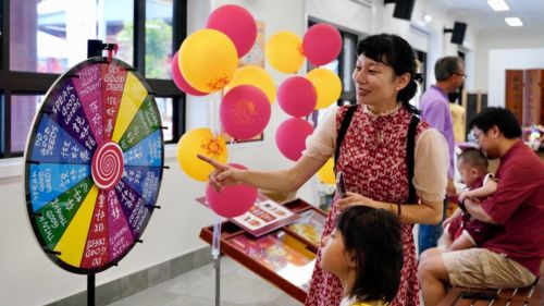 A mum and daughter looking at a spinning wheel at a multicultural event.