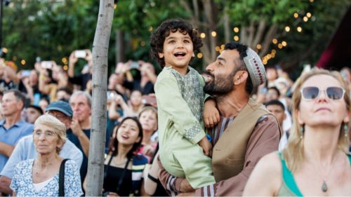 A father holding his young son in a crowd of people.
